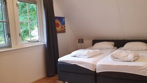 A bedroom with a bed, two bedside tables, a window, and a painting on the wall.