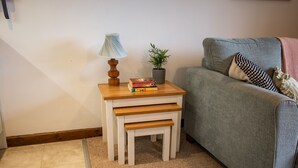 A small wooden nightstand with a lamp, a potted plant, and a few books. - The Linhay (Barnstaple)