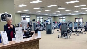 Un gimnasio con máquinas de cardio, pesas y una recepción.