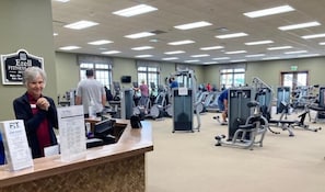 Un centre de remise en forme équipé de machines de cardio, de postes d’entraînement avec poids et d’un comptoir d’accueil.