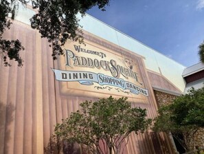 A building facade with a large sign welcoming visitors to Paddock Square, indicating dining and shopping areas. - Walk to Sawgrass: Cottage Villa 2/2 - Glass Lanai/Privacy Fence, Pets Welcome! (The Villages)