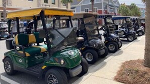 Una fila de carros de golf estacionados en una acera.