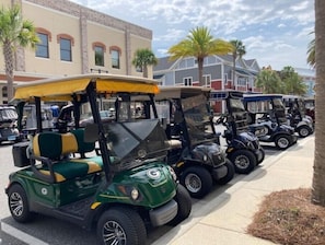 Une rangée de voiturettes de golf est stationnée sur un trottoir.