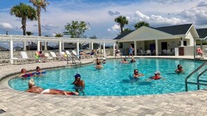 Un área de piscina con sillas de descanso y una zona de estar cubierta.