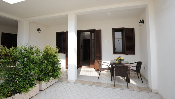 A covered patio area with a table and chairs, a potted plant, and a doorway leading to an interior space. - Cozy apartment in pescoluse maldive del salento A6-7 (Marina di Pescoluse)