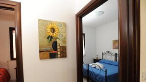 A bedroom with a single bed, a nightstand, and a painting on the wall. - Cozy apartment in pescoluse maldive del salento A6-7 (Marina di Pescoluse)