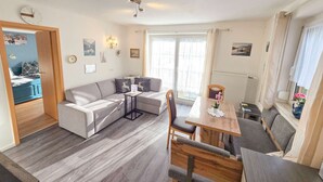 Ein modernes Wohnzimmer mit einer Couch, einem Esstisch und einer Küchenzeile.