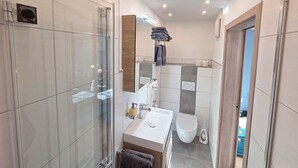 Ein modernes Badezimmer mit Duschkabine aus Glas, einem weißen Waschbecken und einer Toilette.