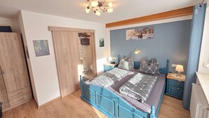 Ein Schlafzimmer mit Bett, Nachttischen, einer Dusche und einem Kleiderschrank. Ein Deckenventilator ist ebenfalls vorhanden.