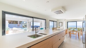 A modern kitchen with a large island, built-in appliances, and a view of the outdoor dining area.
