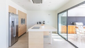 A modern kitchen with a central island, stainless steel appliances, and a glass sliding door leading to an outdoor area.