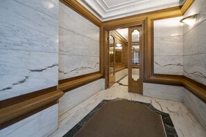 A marble-floored hallway with wooden trim and a carpeted area.