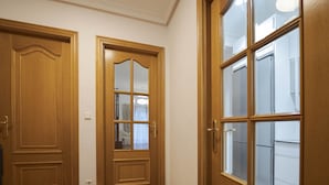 Ein Flur mit zwei Holztüren, eine davon mit Glasschiebepaneel, und einem großen Fenster zur rechten Seite.
