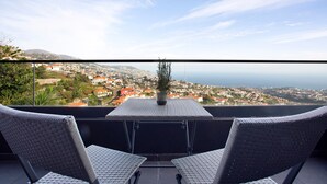 A balcony with two chairs and a table, overlooking a coastal town. - Holiday Home 'Dream View' with Sea View, Private Terrace & Wi-Fi (Funchal)