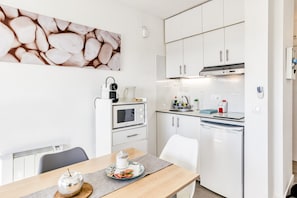 Una cucina moderna con pensili e basi bianche, un forno a microonde, un bollitore e una macchina per il caffè.