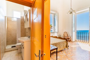 Un dormitorio con cama, una silla, un ventanal y un balcón con vistas.