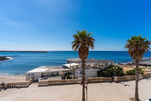 Un bar frente a la playa con vistas al mar, palmeras y cielo despejado.