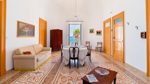 Uma área de refeições com uma mesa redonda, cadeiras, um sofá e piso estampado.