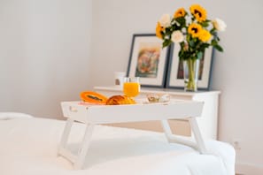 A breakfast tray with a glass of orange juice, a slice of papaya, and a croissant on a white bed. - Seaside Elegance and Tranquility (Porto)
