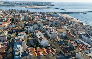 An aerial view of a coastal town with a mix of residential buildings, a beach, and a bridge. - Seaside Elegance and Tranquility (Porto)