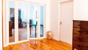 A room with a wooden floor, a dark wooden dresser, and a white door. - Seaside Elegance and Tranquility (Porto)