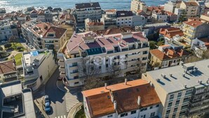 An aerial view of a coastal urban area with multi-story buildings, a visible road, and a body of water in the background. - Seaside Elegance and Tranquility (Porto)