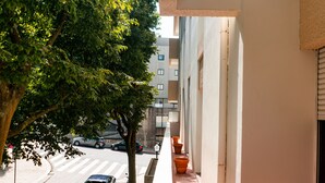 A narrow urban street with parked cars, a pedestrian crossing, and a tree-lined sidewalk. - Seaside Elegance and Tranquility (Porto)