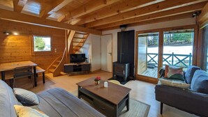 Indbydende interiør i en hytte med trævægge, en sofa, et sofabord, et fjernsyn og en pejs.