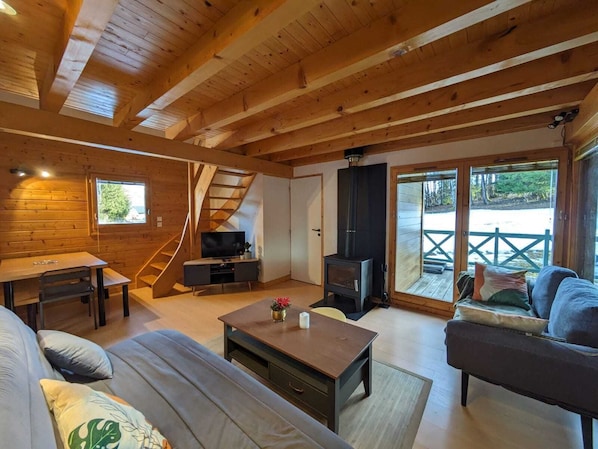 A cozy cabin interior with a wooden interior, a sofa, a coffee table, a TV, and a fireplace. - Chalet nordique au coeur de la Feclaz (La feclaz)