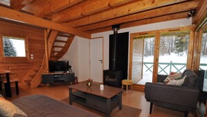 Et hyggeligt interiør i en hytte med en trætrappe, pejs, sofa og fjernsyn.