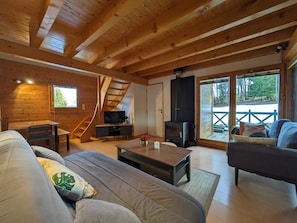 A cozy cabin interior with a wooden ceiling, a sofa, a television, and a fireplace. - Chalet nordique au coeur de la Feclaz (La feclaz)