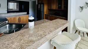 Cozinha moderna com bancadas de granito, eletrodomésticos de aço inoxidável e armários de madeira.