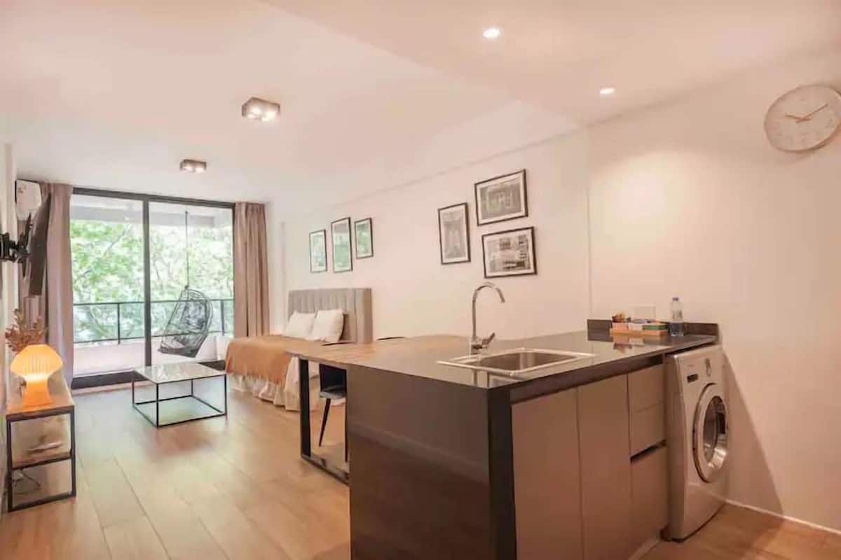 A modern kitchen with a central island, built-in washing machine, and a dining area with a sofa and table.