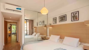 A hotel room with a large bed, a mirror, and a wooden headboard. There is a hallway leading to another room and a window with curtains. - Guatemala Studio 101 (Buenos Aires)