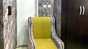 A room with a patterned wall, a door, a wardrobe, and a patterned armchair. - Divine Villa and Resorts LTD (Umu Ezeukwu)