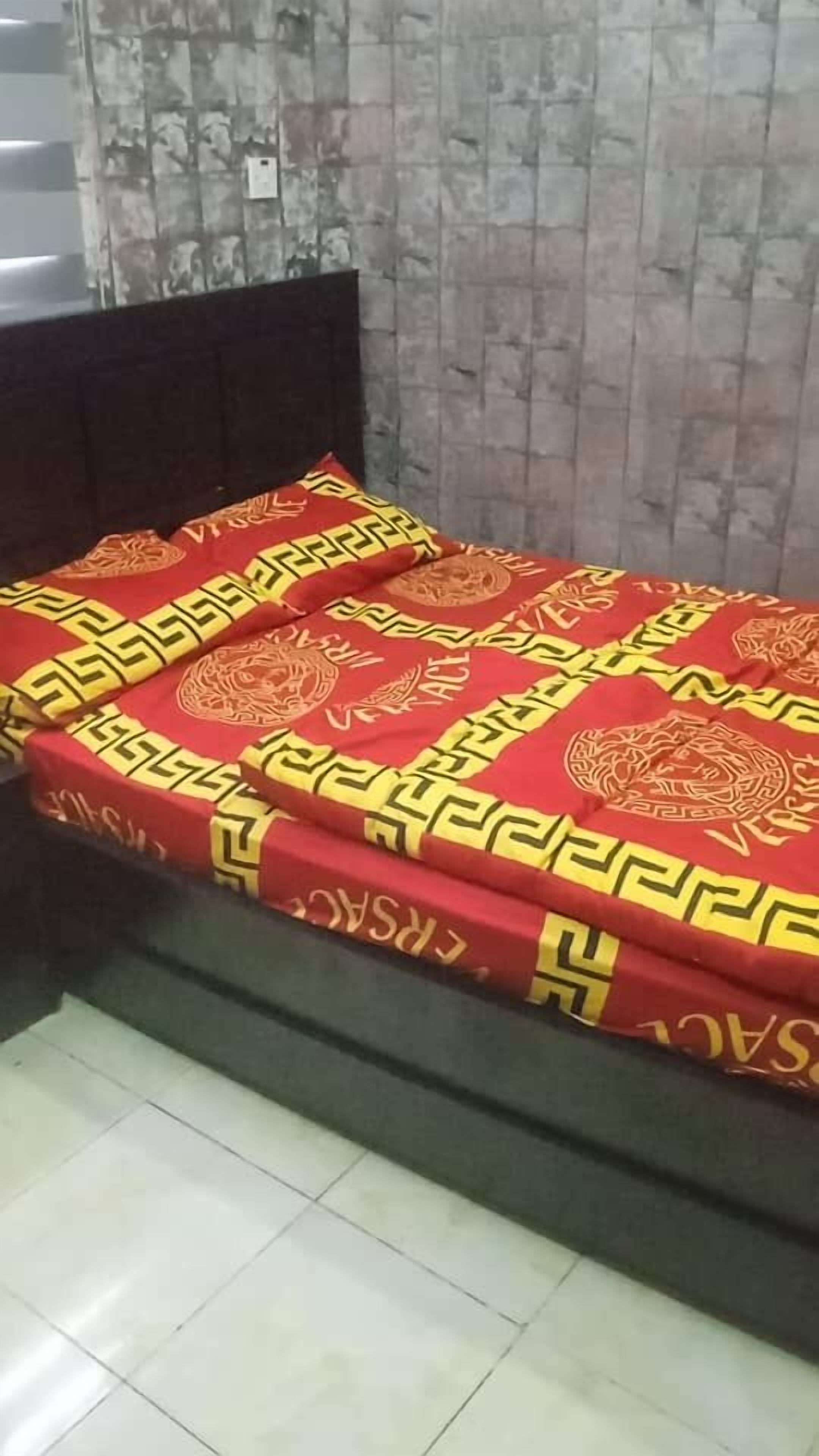 Una cama con una colcha estampada y un cabecero oscuro en una habitación con suelo de baldosas.