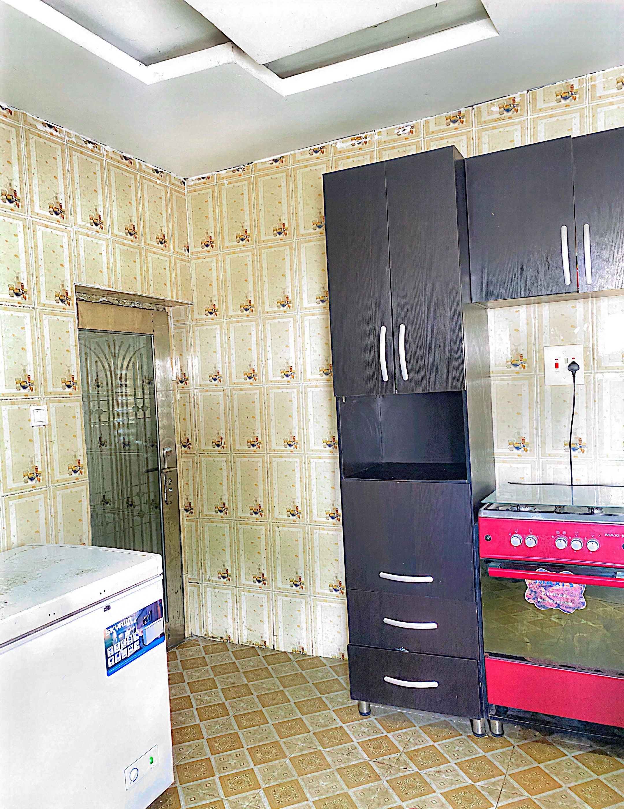 Una cocina con refrigerador, estufa y un mueble negro grande.