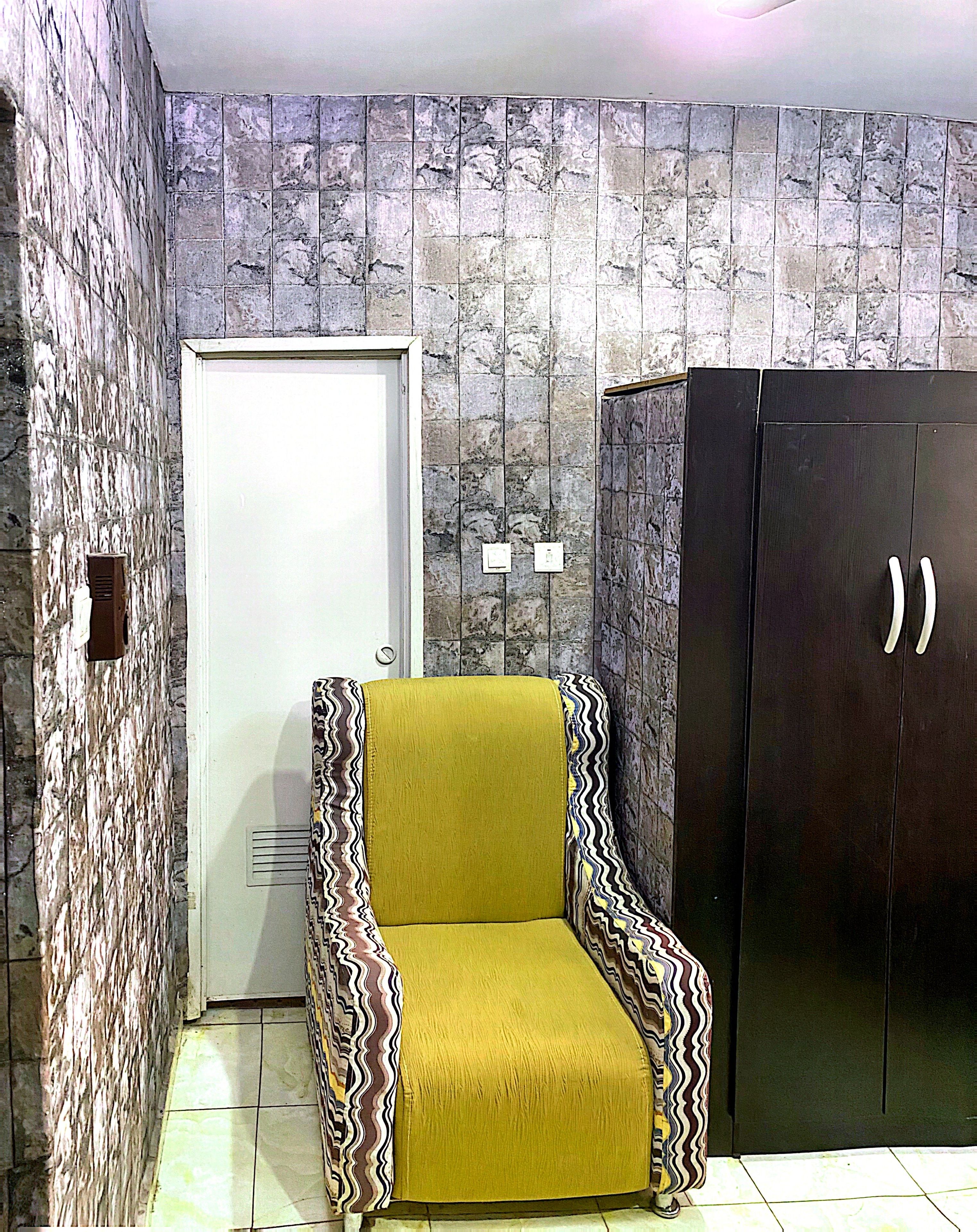 A room with a patterned wall, a door, a wardrobe, and a patterned armchair.