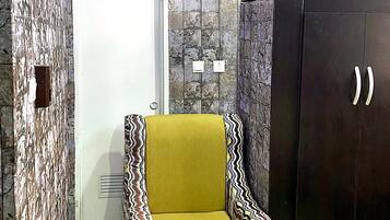A room with a patterned wall, a door, a wardrobe, and a patterned armchair.