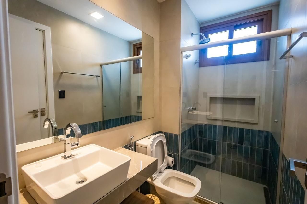 Ein Badezimmer mit einem großen Spiegel, einem Waschbecken, einer Toilette und einer Duschkabine.
