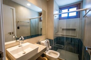 Une salle de bain avec un grand miroir, un lavabo, des toilettes et un espace douche.