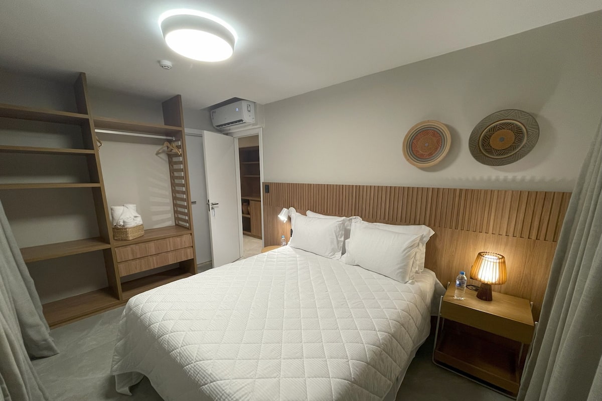 Une chambre d’hôtel avec un lit, une table de chevet, une armoire et un luminaire au plafond.