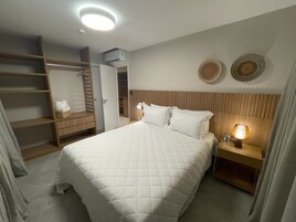 Una habitación de hotel con cama, mesita de noche, armario y luz en el techo.