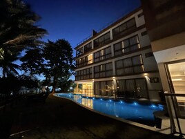 Un hotel de varios pisos con piscina, ventanas amplias y un balcón.