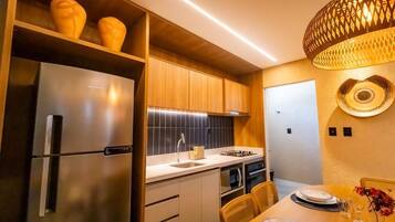 Una cocina moderna con armarios de madera, un refrigerador de acero inoxidable y un comedor con una mesa dispuesta para dos.
