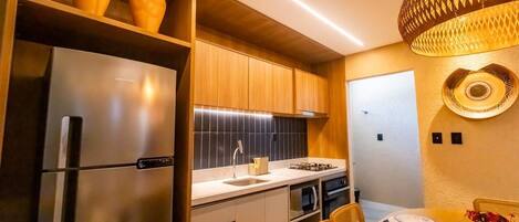 Une cuisine moderne avec des meubles en bois, un réfrigérateur en acier inoxydable et un coin repas avec une table dressée pour deux personnes.