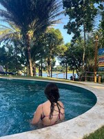 Una piscina al aire libre, sombrillas, sillones reclinables de piscina