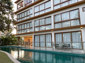 Een hotel met meerdere verdiepingen, een zwembad, terras en grote ramen.