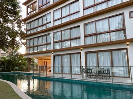 Um hotel com vários andares, piscina, área de estar externa e grandes janelas.