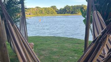 A hammock in a grassy area with a lake and trees in the background.